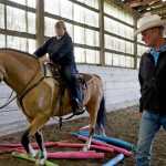 Bill Cameron trains Laura Baker on her horse, Maverick, at Swampy Acres on Thursday.