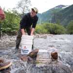 Cameron Jardell pauses while scooping sediment into a sluice box in Gold Creek near Basin Road on Friday. Corey Box, left, is a self-taught gold panner, who says he learned by watching YouTube videos, and has been panning for a week at Gold Creek. Jardell joined Box for the day.