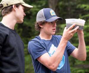 Cameron Box points out flakes of gold in a container with sediment to Cameron Jardell at Gold Creek near Basin Road on Friday. Box is a self-taught gold panner, who says he learned by watching YouTube videos, and has been panning for a week at Gold Creek. Jardell joined Box for the day.
