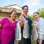 Sisters (from left to right) Jennifer Mooney, Toni Rae Sanderson and Mary Anna Shay hold up salmon they are about to smoke in Hydaburg. Photo by Bethany Goodrich.