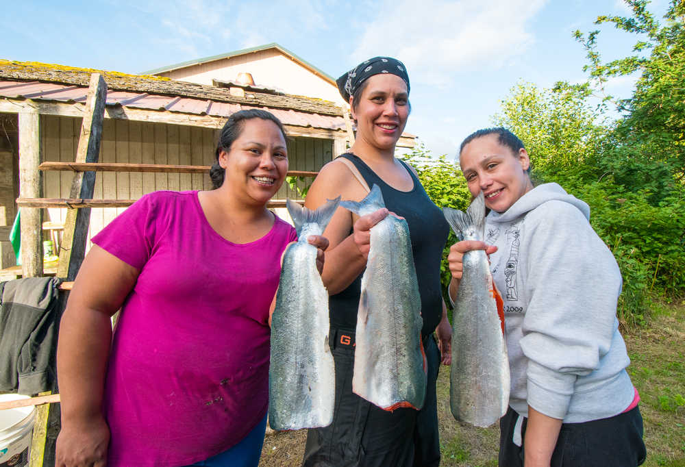Sisters (from left to right) Jennifer Mooney, Toni Rae Sanderson and Mary Anna Shay hold up salmon they are about to smoke in Hydaburg. Photo by Bethany Goodrich.