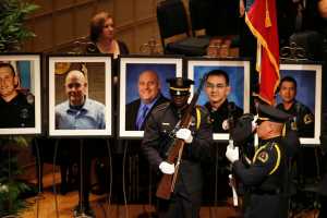 Portraits of the five fallen police officers are seen at rear as a memorial gets underway at the Morton H. Meyerson Symphony Center in Dallas, Tuesday, July 12, 2016, after the arrival of President Barack Obama. Five police officers were killed and several injured during a shooting in downtown Dallas last Thursday night.