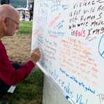 Michael Sleischhauer adds an anti-discrimination message to a white board during the Juneau Police Department's event for those that want to "be counted as a person against violence, against discrimination, and against hate" at Marine Park on Wednesday.