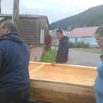 Carver Steven Price (center), son of master carver Wayne Price, and community members help carry the steamed-open canoe in Hoonah.