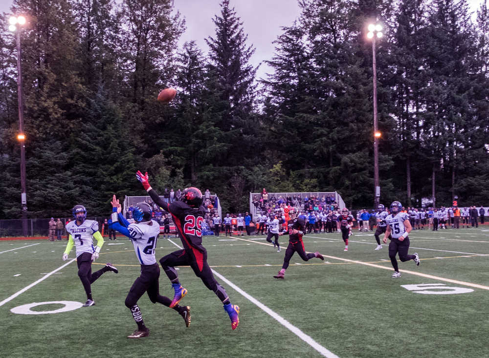 Thunder Mountain junior Jacob Tapia (20) and Juneau-Douglas junior Tyler Collins (29) battle downfield for position during Saturday's game at Adair Kennedy Field. TM won 50-20.