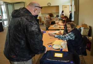 Poll worker Linda Hollinbeck smiles as she gives a "I Voted" sticker to Kevin Poole on Tuesday at the Mendenhall Valley Public Library during Alaska's statewide primary. Tuesday was the first time an election was held at the library, which opened in October.