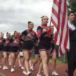 The Juneau-Douglas High School cheerleaders bring in the colors during the Crimson Bears football game against Kodiak High School on Saturday at Adair Kennedy Field. JDHS lost 26-20.