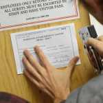 James Barrett of Rainforest Farms staples his business's new license to a wooden board in at the cannabis farm's entry. Rainforest Farms is the first cannabis farm in Juneau to receive a state license and begin growing.