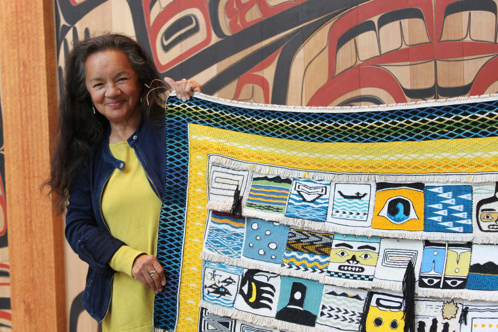 Master weaver Clarissa Rizal holds up one end of the "Weavers Across the Water" Chilkat and Ravenstail blanket. Forty Ravenstail and Chilkat weavers contributed a square measuring around five inches by five inches. Rizal wove the border around the robe, a pattern called "Mating Loons," and is working them all into a robe that will get its first use during the dedication ceremony for Xunaa Shuka Hit, the Glacier Bay tribal house.