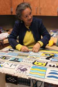 Master weaver Clarissa Rizal speaks with friend and fellow weaver Della Cheney as they work on the "Weavers Across the Waters" robe that will first be worn at the dedication of Xunaa Shuká Hít, the Huna Tribal House, in Glacier Bay.