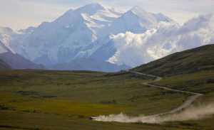 FILE - In this Aug. 8, 2013, file photo, a tour bus kicks up dust during a sunny day at Denali National Park in Alaska as Mount Denali appears in the background. Activists protested outside a state office building in Fairbanks, Alaska, on Aug.10, 2016, to demand Alaska Gov. Bill Walker to end wolf hunting near the park in light of its declining wolf population (AP Photo/Manuel Valdes, File)