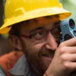 Harrison Voegeli peers through a relascope as he inventories the Tongass. A relascope is used to find height, diameter and basal area of trees.