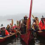 Carver James Hart greets the hundreds gathered on Bartlett Cove's shore in Tlingit. These three boats paddled from Hoonah to Glacier Bay.