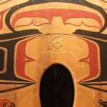 Kaasteen is the central figure in Xunaa Shuká Hít's interior house screen. According to oral history, Kaasteen caused the advance of the glacier that forced the Huna Tlingit to flee Glacier Bay. In some versions of the story, she stayed behind; in others, her grandmother stayed in her place. People gifted her with sea otter furs, hanging over the doorway at center, so she could stay warm. Her eyes are abalone, reflecting the glacier as it advances.