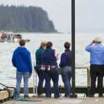 Family members and spectators watch the recovery of Arnold Skeek from the end of the Don D. Statter Memorial Boat Harbor float in Auke Bay on Monday. Skeek, 27, was believed to have fallen off a boat anchored about a half mile outside the harbor on Aug. 14.