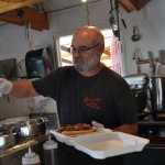 Randy Sutak, owner of Randy's Rib Shack, pours some of his signature barbeque sauce over a pulled pork and briscuit sandwich. Sutak starting perfecting his sauce recipe eight years ago.