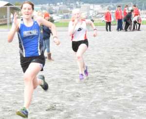 Thunder Mountain High School senior Meghan Penrose outsprints Juneau-Douglas High School sophomore Gretchen Neal at the finish of the Juneau Mini Meet at Savikko Park on Saturday.