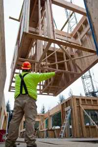 Royal Hill, of Triplett Construction, directs a lift operator in the placement of a stairwell module at the Housing First project on Allen Court on Monday.