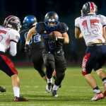 Thunder Mountain's Roy Tupou runs between the blocking by teammates Kyrel Payne, left, and Chilton Dawson, right during their game against North Pole at TMHS on Friday. TMHS won 22-20
