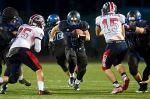 Thunder Mountain's Roy Tupou runs between the blocking by teammates Kyrel Payne, left, and Chilton Dawson, right during their game against North Pole at TMHS on Friday. TMHS won 22-20