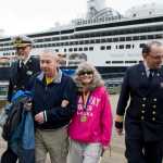 Escorted by Captain PJ van Maurik, left, and Hotel Director Francois Birarda, right, Wendy Yoisten, with her husband John, of St. Albert, Alberta, arrives in Juneau as the one millionth cruise ship passenger for the season in Juneau on Thursday. The Yoisten arrived on the Holland America Line Zaandam.