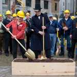 John Venables, center, dressed up as William Henry Seward watches as Assemblymember Mary Becker turns over a shovel of dirt during a ceremonial groundbreaking Thursday for a Seward statue in the Dimond Courthouse Plaza.