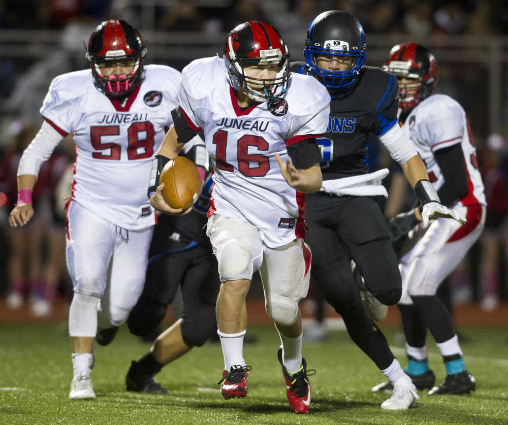 Juneau-Douglas's quarterback Maximus Wheat is chased by Thunder Mountain's Dominique Maua in a cross town conference game at TMHS on Friday. TMHS won the game.