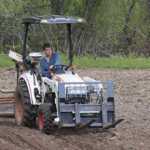 Tim drives a tractor for the first time post-stroke. He is raking George Campbell's potato field before planting commences in May 2014.