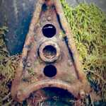 The tail end of a rusty vintage car.