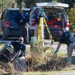 Juneau Police Department Sgt. Nick Garza retrieves a wheelchair while officers investigate the site where an adult male was found dead along the bike path near Mendenhall Loop Road and Egan Drive on Thursday.