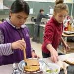 Eighth-graders Joselle Lopez, left, and Luna Ewing work on making their grilled-cheese sandwiches during a Life Skills class at Dzantik'i Heeni Middle School on Thursday.