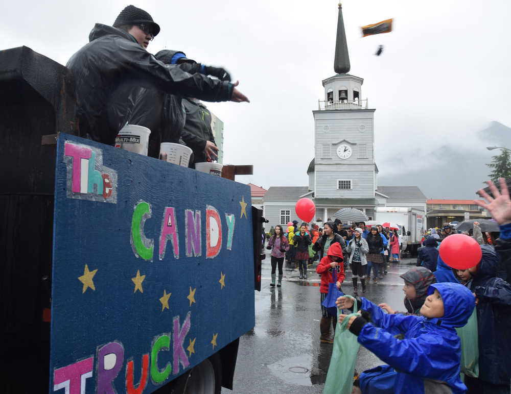 Kids hold open plastic grocery bags to catch candy hurled from parade floats during Sitka's Alaska Day parade on Tuesday, Oct. 18, 2016.