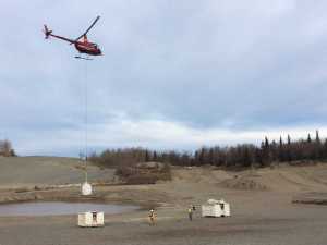 A helicopter brings a 700-pound sack of car parts to a trash bin on Wednesday, Oct. 19, 2016, in Anchorage, Alaska. More than 2,000 cars were dumped over a bluff above a wildlife refuge after the 1964 Good Friday earthquake, and a clean up effort to remove about 100 of those cars imbedded in the bluff has been going on for nine years. (AP Photo/Mark Thiessen)