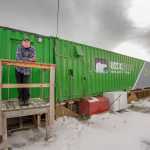 In this Oct. 26 photo provided, employee Joe Carr stands outside a new indoor hydroponics farm owned by a local Alaska Native corporation in Kotzebue. Arctic Greens is harvesting kale, various lettuces, basil and other greens weekly from the soil-free system and selling them at the supermarket in the community of nearly 3,300.