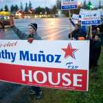Juan Muñoz waves a large sign for his wife, Rep. Cathy Muñoz, during the evening commute on the eve of the national and state elections Nov. 7, 2016.