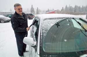 Blaine Hollis brushes off a dusting of snow on his car at the Mendenhall Mall on Tuesday, Nov. 22, 2016.