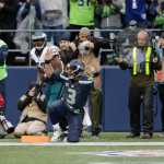 Seattle Seahawks quarterback Russell Wilson (3) gets up and signals the touchdown after he caught a pass from wide receiver Doug Baldwin to score a touchdown ahead of Philadelphia Eagles outside linebacker Nigel Bradham (53) in the second half of an NFL football game Nov. 20 in Seattle. (John Froschauer | The Associated Press)