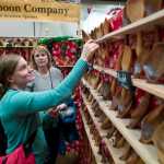 Aurah Landau, left, examines spoons at the Alaska Wooden Spoon Company of Anchorage booth at Public Market in Centennial Hall on Friday.