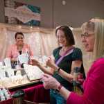 Jodie McDonnell, right, and Helen Phillips, center, look at jewelry by Melissa Harrison of Sitka at her Tidal Beadworks booth at Public Market in Centennial Hall on Friday.