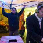 Carl Liberty keeps the winds from blowing away a portable rain shelter at Manuel Hernandez, aka DJ Manu, keeps the music going on Front Street during Gallery Walk on Friday, Dec. 2, 2016.