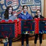 From left, Nyla Duncan, Alyse Duncan and Emma Gassman hold up the felt panels their grandmother, Pauline Duncan, had in her first grade classroom in Sitka. They visually tell the story of how Raven brought fire to the world, as does one of the three books Duncan wrote and Lindsay Carron illustrated, released by Sealaska Heritage Institute Dec. 10.