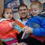 Jeff Ketah holds Selena, 2, and Dexter, 5, as they hold "10 Sitka Herring," written by Pauline Duncan and illustrated by David Lang.