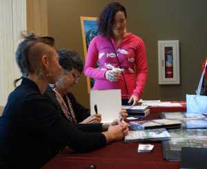 Crystal Worl, illustrator of the newly released two-book Tlingit alphabet, gets books signed by author Pauline Duncan and ilustrator Lindsay Carron.