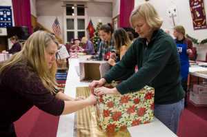 Rotary members Leah Van Kirk, left, and Amy Lujan wrap boxes with others as part of the Racheal MacLeod Christmas Dinner Box Project at The Salvation Army Church on Monday, Dec. 19, 2016. The boxes, which will contain all the ingredients for a holiday dinner, will be available Thursday and Friday to 360 local families. The project is coordinated by the three Rotary clubs and the Rotaract club of Juneau.