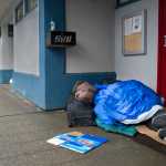 A homeless man sleeps in the doorway of the Filipino Community Hall on Wednesday, Dec. 21, 2016.