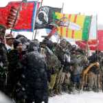 FILE - In this Dec. 5, 2016, file photo, military veterans and Native American tribal elders come to a stop for a ceremonial prayer during a march to a closed bridge across from the Dakota Access oil pipeline site in Cannon Ball, N.D. Some Native Americans worry the transition to a Donald Trump administration signals an end to eight years of sweeping Indian Country policy reforms. But Trump's Native American supporters said they're hopeful he will cut through some of the government red tape that they believe has stifled economic progress on reservations. (AP Photo/David Goldman, File)