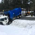 A garbage truck is pulled out of the snow after it slid off View Drive on Dec. 20.