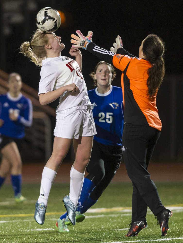 Juneau-Douglas' Erika Holst attempts to head the ball over Thunder Mountain's goalie Tianna Huber as Thunder Mountain's Meghan Penrose looks on at Adair-Kennedy Memorial Park on April 8.