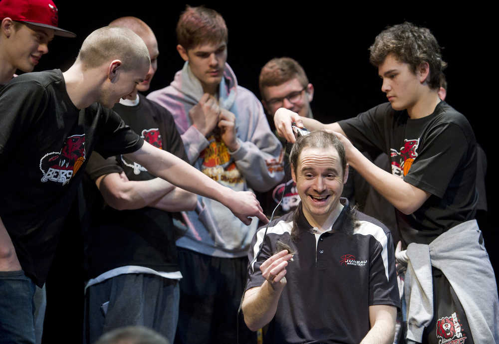 Juneau-Douglas High School head basketball coach Robert Casperson gets his hair cut on stage by senior Treyson Ramos during a school assembly on March 30, holding up his end of the bargain that he would shave his head if his team won the state championship title. JDHS beat Dimond High School in Anchorage 38-31 for the championship. It was the first time since the 1997-1998 season that the Crimson Bears won the title.
