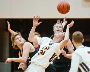 Juneau-Douglas' Kasey Watts, left, and teammate Erik Kelly play a loose ball against Dimond's Ric Jenkins, center, during the Capital City Classic at JDHS on Friday, Dec. 30, 2016.
